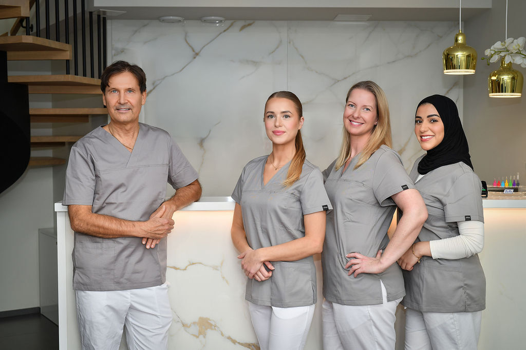 Fire tannhelseeksperter ved Drammen Tannlegesenter, fotografert i moderne resepsjonsområde med vennlig og profesjonell fremtoning.